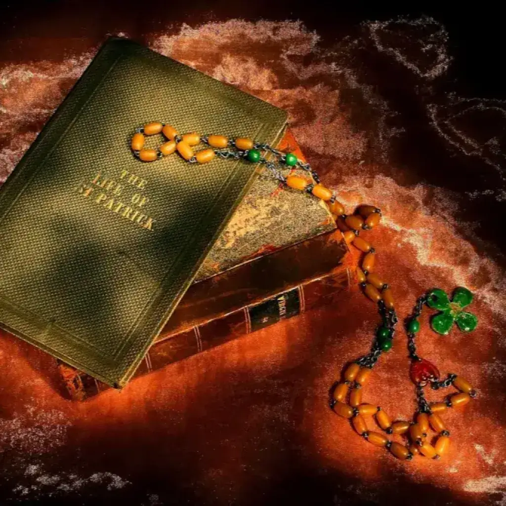 Vintage 'The Life of St Patrick' book with rosary and shamrock in warm light