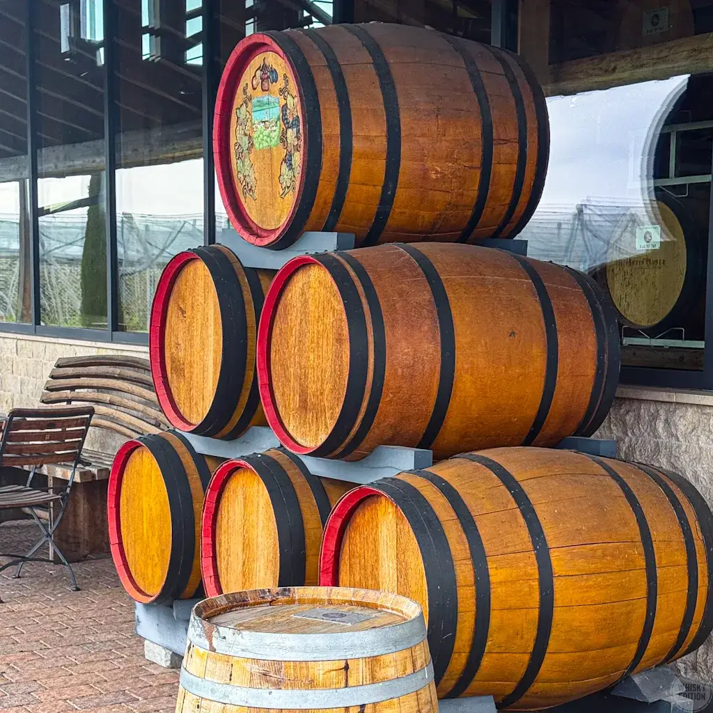 Stacked wooden barrels with the Steinhauser crest outside the distillery