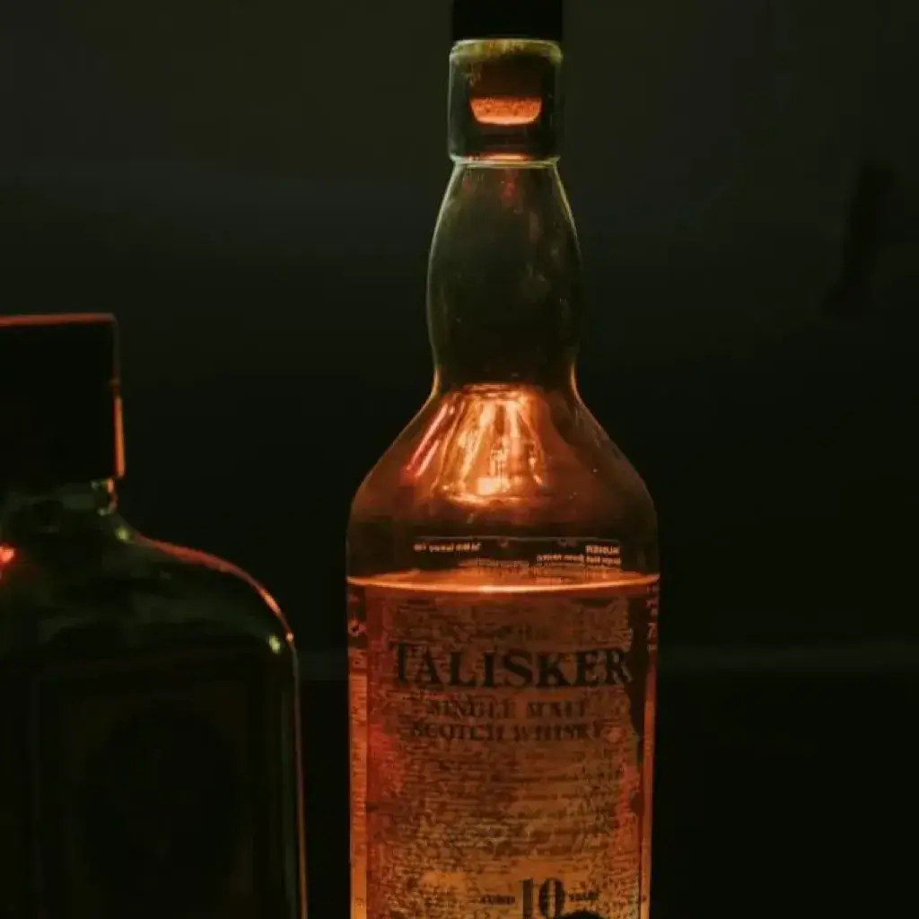 Backlit whisky bottle in moody darkness