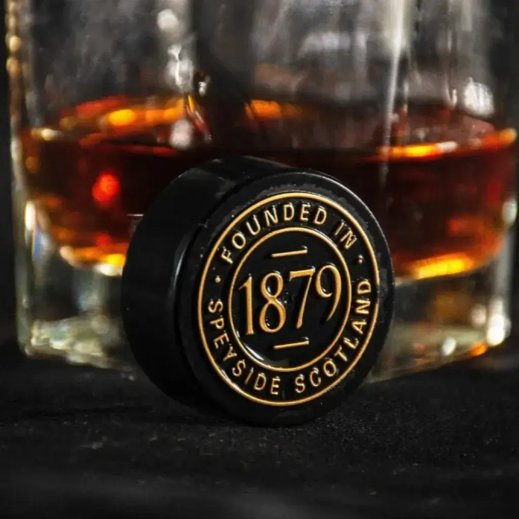 Speyside cork in front of a whisky glass with amber liquid on a dark background
